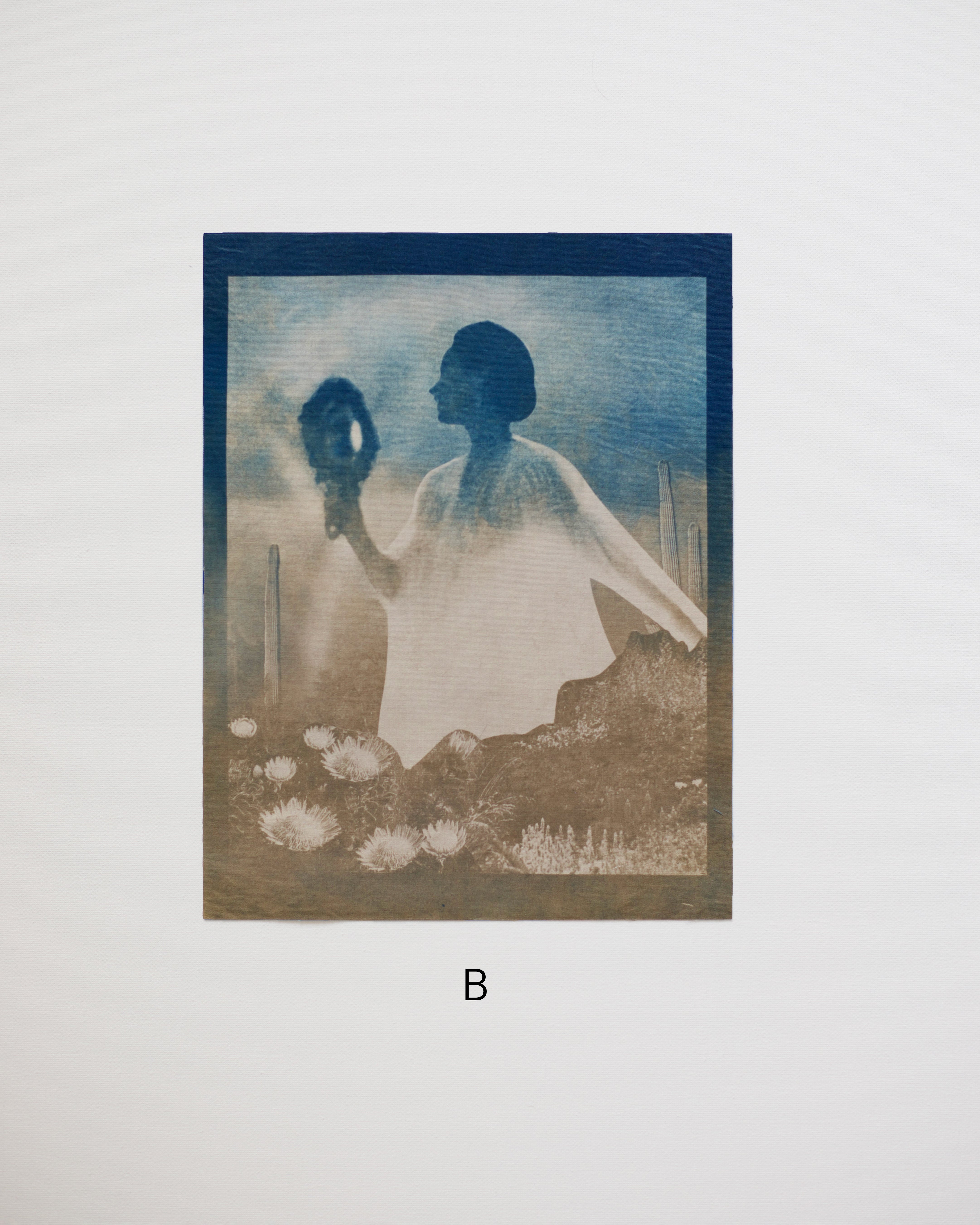 blue cyanotype print of a woman holding a mirror with a blue and brown color scheme.